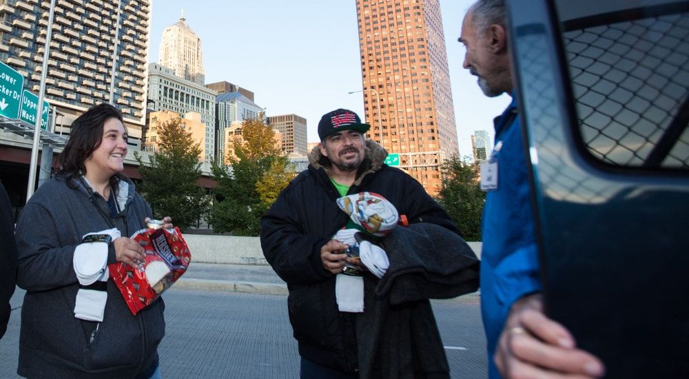 A staff member with The Night Ministry provides clothing to clients on the streets.